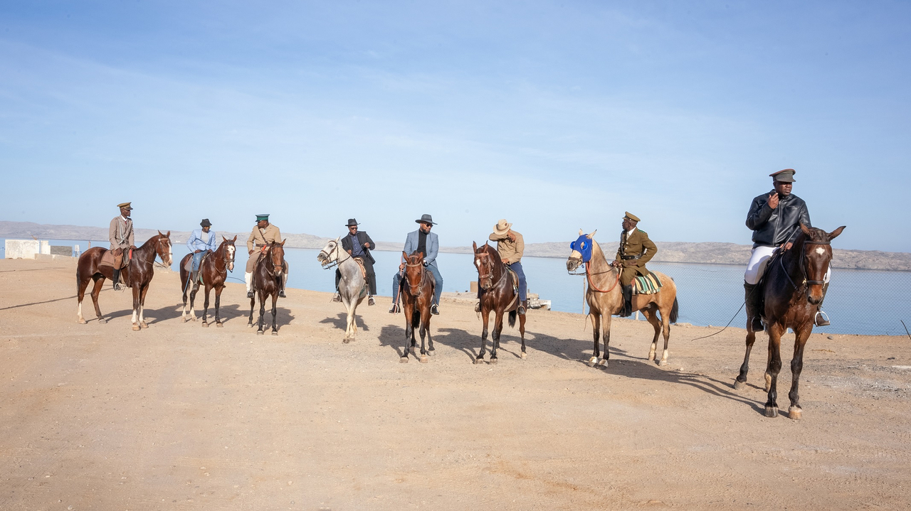 Mehrere schwarze Reiter in Uniformen der Kolonialzeit an Sandstrand